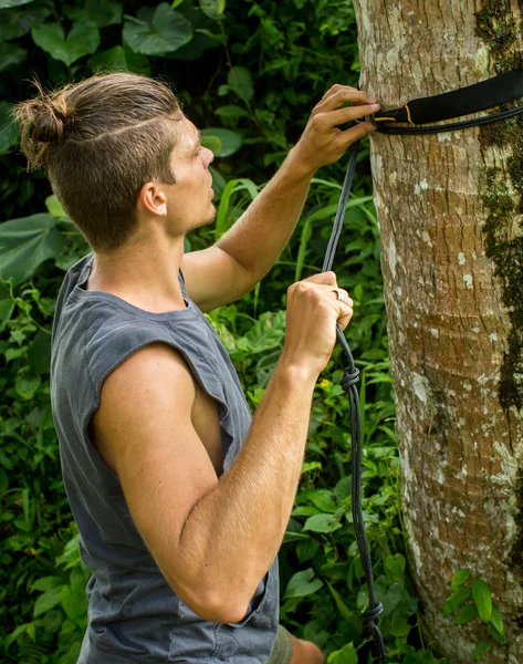 Jovem pendura uma rede em uma árvore — Fotografia de Stock