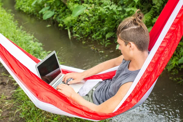 Homem na rede trabalhando no laptop durante as férias de verão . — Fotografia de Stock