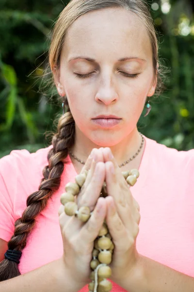 Γυναίκα κατέχει ένα κομπολόι στα χέρια του και να προσεύχονται — Φωτογραφία Αρχείου