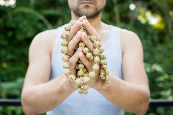 Genç adam bir tespih tutan elleri ve dua — Stok fotoğraf