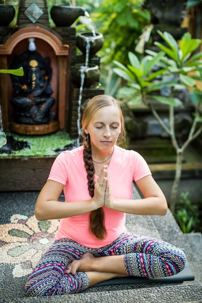 Mujer practicando meditación contra bosque tropical — Foto de Stock