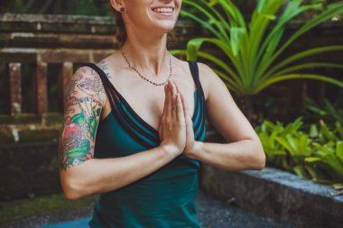 Genç bir kadının huzurlu ortamda açık havada meditasyon yapması