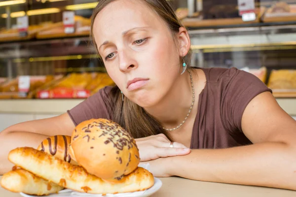 Una mujer joven y guapa comiendo dulces en el café. Malos hábitos. Sanidad —  Fotos de Stock