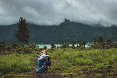 Genç kadın oğlunu dağ ve göl bir arka plan üzerinde sarılma