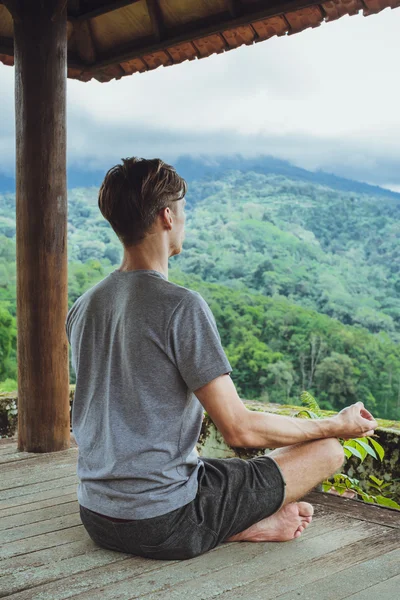 Divatos fiatalember meditál a pavilonban, a háttérben — Stock Fotó