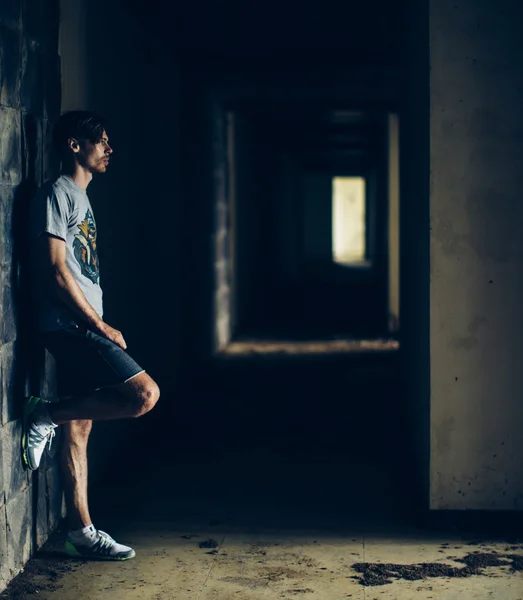 Hipster na moda em um prédio escuro abandonado — Fotografia de Stock
