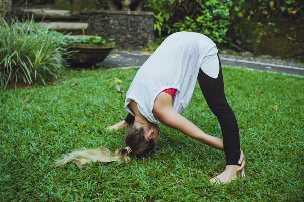 Молода жінка займається вправами йоги вперед згинається. Тоноване зображення — стокове фото