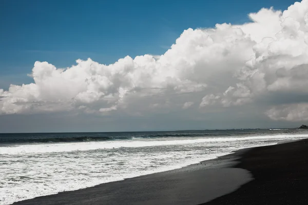 Rocha vulcânica baseada praia de areia preta — Fotografia de Stock