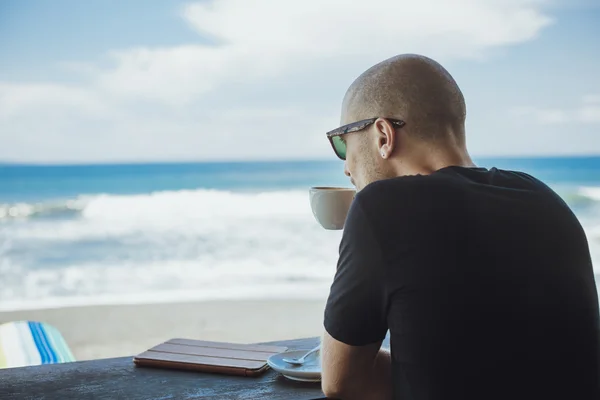 Jovem com sua xícara de café da manhã olhando para o oceano vi — Fotografia de Stock