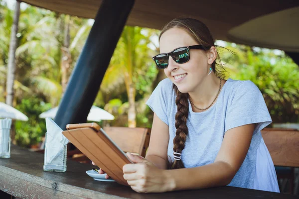 Young woman drinking coffee and watching at tablet at restaurant — 스톡 사진