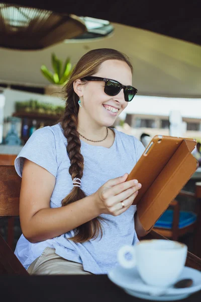 Mujer joven bebiendo café y viendo en la tableta en el restaurante — Foto de Stock