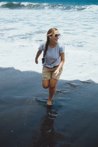 Mladá žena běžící na písku poblíž oceánu, Bali. — Stock fotografie