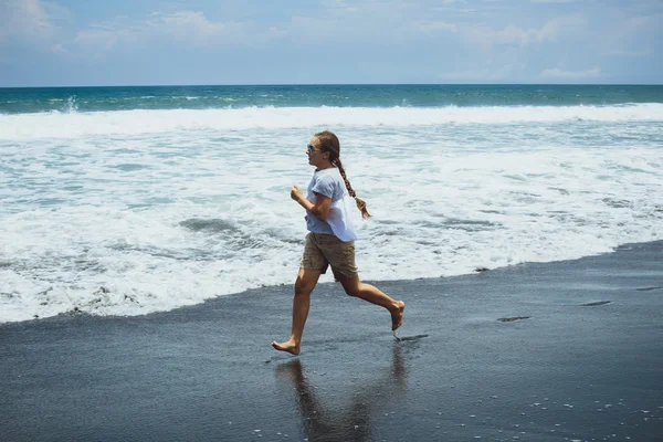 Jeune femme courant sur le sable près de l'océan, Bali . — Photo