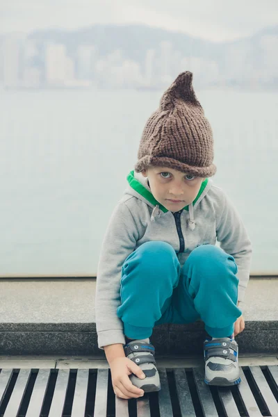 5 anno-vecchio ragazzo in un divertente cappello è seduto e riposo su il passo — Foto Stock