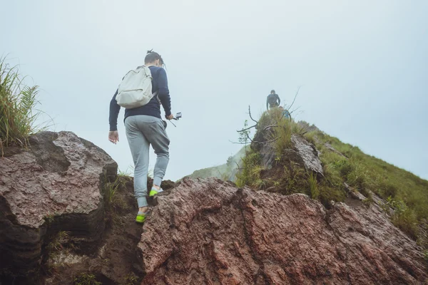 3 Homens caminham ao longo da colina com mochilas e com nuvens brancas a — Fotografia de Stock