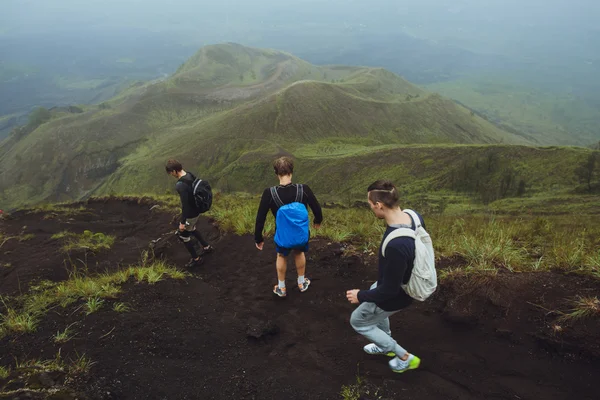 3 Men walk along the hill with backpacks and with white clouds a — Stock Photo, Image