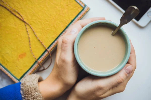 Laptop e tazza di caffè nelle mani di una ragazza seduta su uno schienale di legno — Foto Stock