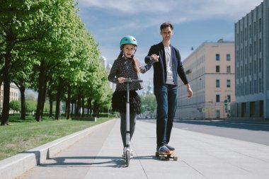 Baba ve kızı bir scooter ve paten birlikte binmek