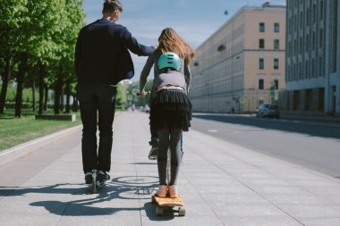 Baba ve kızı bir scooter ve paten birlikte binmek