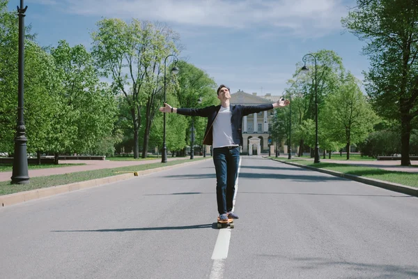 Uomo di moda su uno skateboard in città — Foto Stock