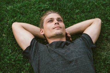 Çekici genç adam yalan her iki ellerini dinlenme arkasında onun Ne ile