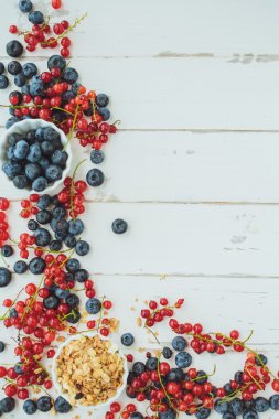 Kırmızı kuş üzümü, yaban mersini ve müsli Beyaz ahşap zemin üzerinde