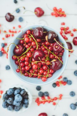 Yaban mersini ve bir beyaz tahta üzerinde mavi bir kova kırmızı kuş üzümü 