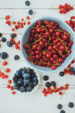 Yaban mersini ve bir beyaz tahta üzerinde mavi bir kova kırmızı kuş üzümü 