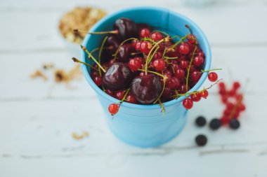 Kırmızı kuş üzümü, yaban mersini ve müsli Beyaz ahşap zemin üzerinde
