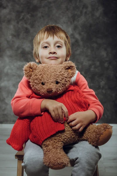 Ragazzo 5 anni abbraccio grande orsacchiotto si siede su una sedia — Foto Stock