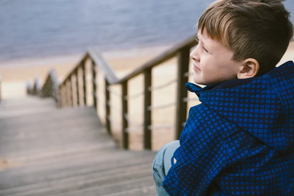 Chlapec na schodech u jezera. Čekání koncept — Stock fotografie