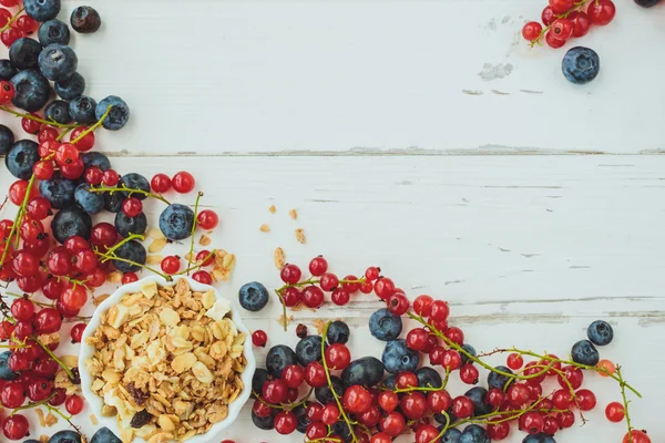 Grosellas rojas, arándanos y muesli sobre fondo de madera blanca — Foto de Stock