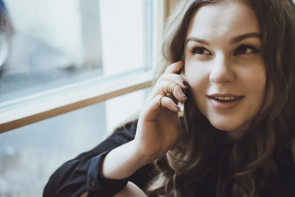 Hermosa mujer joven hablando por teléfono mientras está sentada junto al viento — Foto de Stock