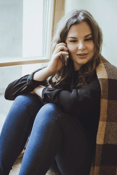 Hermosa mujer joven hablando por teléfono mientras está sentada junto al viento — Foto de Stock