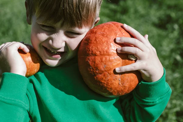 Тыква в руках 5-летнего мальчика в зеленом свитере — стоковое фото