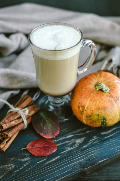 Spicy pumpkin latte on a wooden board with a sweater