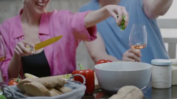 Joyeux couple préparant de la salade fraîche à la maison. Femme blonde et son mari dînent dans la cuisine — Video