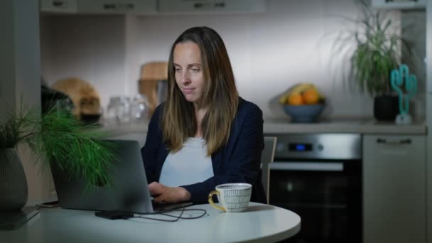 Mujer freelancer escribiendo en un portátil mirando la pantalla de la computadora trabajando en casa — Vídeos de Stock