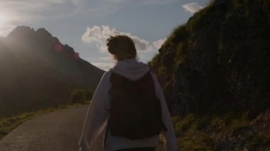 Rastalı ve sırt çantalı bir kadının Karadağ 'da gün batımında dağ manzarasının arka planında milli parkta yürüyüşü. Kadın motivasyon macerası yaşıyor..