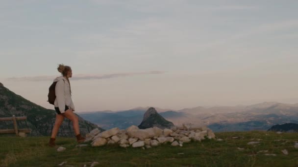 Viagem Millennial mulher com dreadlocks olha para o céu, senta-se no topo da montanha. Conceito de viagem individual — Vídeo de Stock