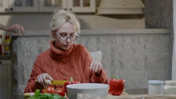 Pareja de familia feliz preparando comida en casa. Hombre guapo y mujer rubia con copa de vino cenan en la cocina — Vídeos de Stock