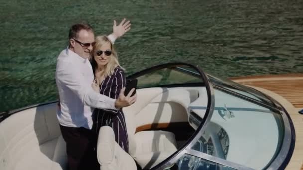 Szczęśliwa Romantyczna para w okularach przeciwsłonecznych robi selfie video na motorówce pływającej na otwartym morzu. Kobieta i mężczyzna robią zdjęcia z telefonu komórkowego podczas podróży statkiem podczas wakacji. — Wideo stockowe