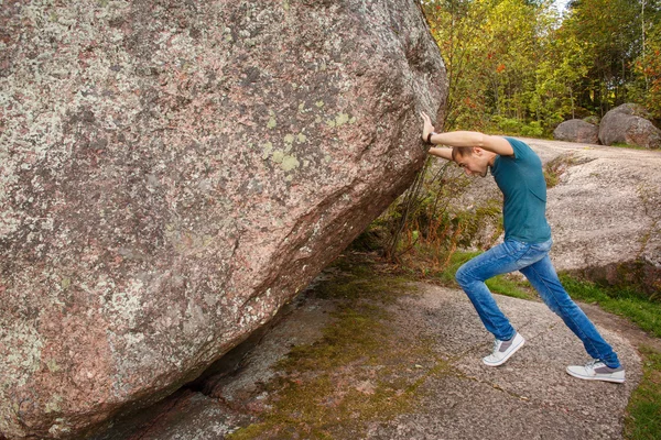 Homem com mochila empurrando uma pedra enorme — Fotografia de Stock