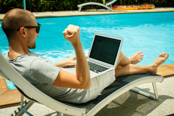 Человек с ноутбуком у бассейна — стоковое фото