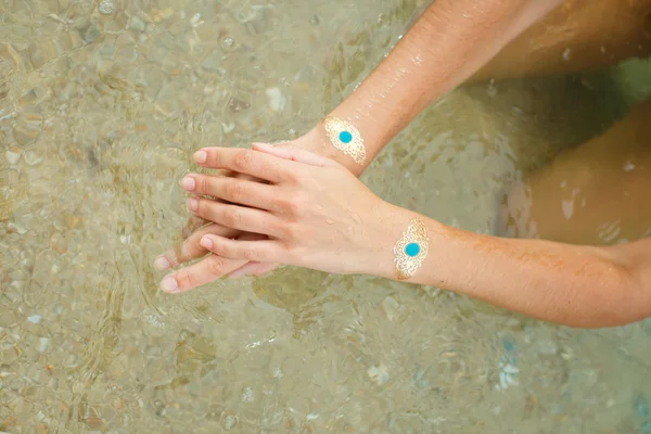 Woman's hands legs with sticker tatoo in the sea — Stock Photo, Image