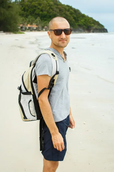 Fiatal utazó ember egyedül sétálni a tengerparton hátizsák. — Stock Fotó