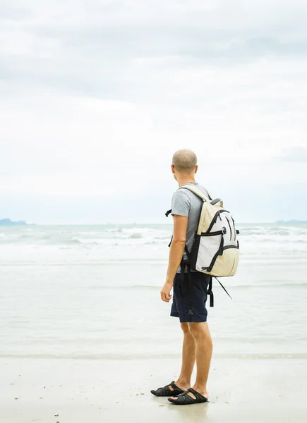 Молодий мандрівник з рюкзаком, що йде один на узбережжі . — стокове фото