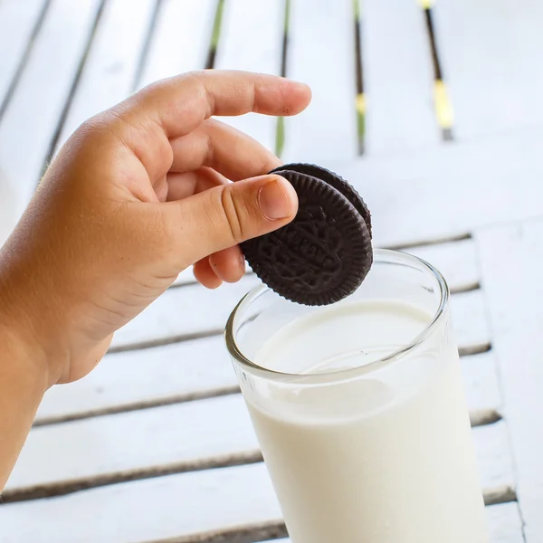 Barnets hand med Oreo cookies sträcker sig till mjölk — Stockfoto