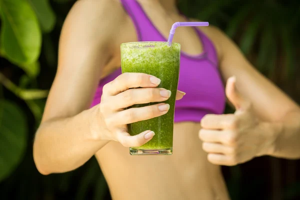 Athletic girl holding a green smoothie — Stock Photo, Image