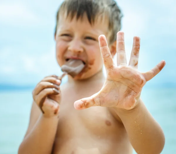 Niño comiendo helado de chocolate en el mar — Foto de Stock